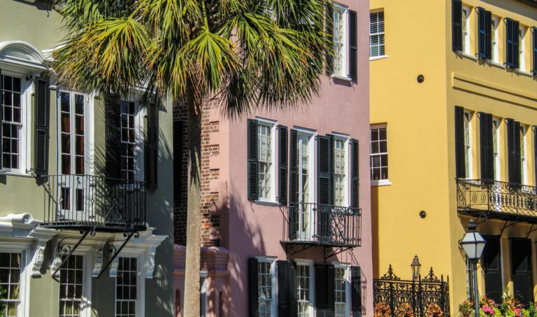 Pastel row houses and palm trees on a street in Charleston, South Carolina.
